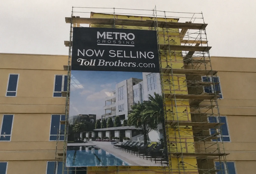 Temporary banner sign on construction fence — short-term promotional signage